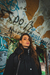 Mujer joven viendo a cámara en frente de una pared con arte callejero