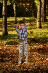 Boy throws leaves in the air.