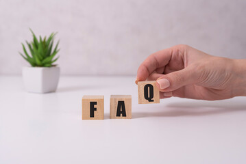 Businessman puts wooden blocks with the word FAQ frequently asked questions . Collection of...