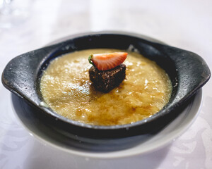Delicious cream brulee with brownie and strawberry in a rustic plate