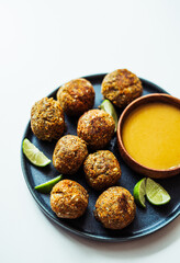 Bolitas de garbanzo y zanahoria estilo falafel, acompañado de un plato de ensalada de pasta y un aderezo