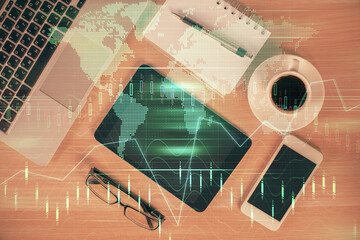 Double exposure of financial graph hologram over desktop with phone. Top view. Mobile trade...