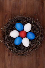 Nest with painted eggs on a wooden table. Top view.