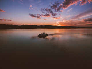 Gorgeous orange-goldlike sunset over the river with floating cruise boat. Almost dusk.
