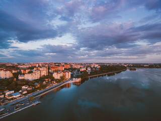 Obraz premium Sunset over a river with view on city embankment and city. Warm time of the year. Golden hour.