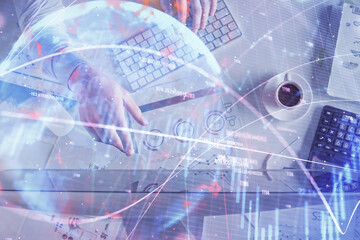 Multi exposure of man's hands typing over computer keyboard and forex graph hologram drawing. Top view. Financial markets concept.