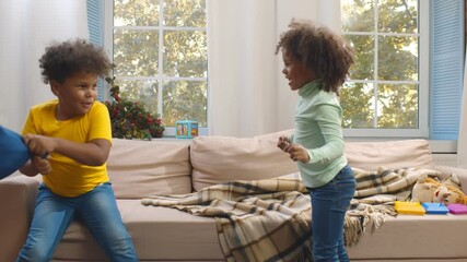 Laughing african kids having fun while pillow fight in living room