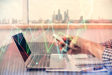 Plakat Double exposure of man's hands holding and using a digital device and forex graph drawing. Financial market concept.