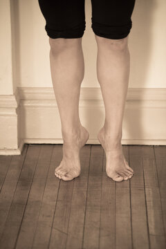 Legs and feet of female dancer on tip-toes on wood floor. Sepia toned image in dance studio.