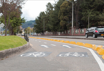 Bike path in middle of a highway with a black mountain bike trees and a car at background....