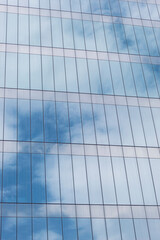 Closeup to a blue cloudy sky reflecting on a modern skyscraper window. Symmetry and architecture concept