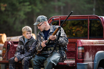 Father in a cap and his son sitting in a car after the hunt.