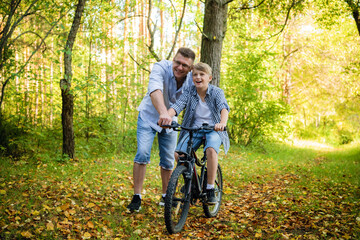 Obraz na płótnie Canvas Father Teaching Son To Ride Bike In Countryside