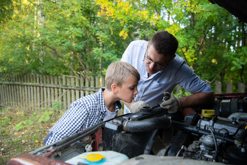 Dad and his son repairing car with open hood outdoors, fixing engine - 386535308