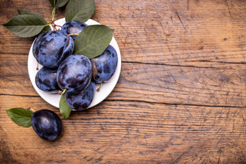 heap of a purple damsons plums over grunge wooden background. natural fruits. healthy eating concept