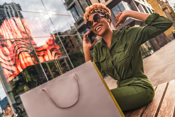 Happy stylish lady stretching after shopping in the city