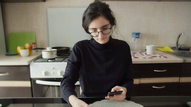 girl makes an online order using a phone and a visa card at home in the kitchen
