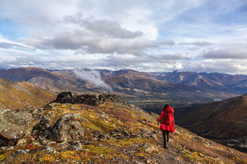 Fototapeta premium Woman Backpacking along Scenic Hiking Trail surrounded by Mountains in Canadian Nature. Taken in Tombstone Territorial Park, Yukon, Canada.