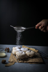Fresh homemade donuts with powder sugar on the black dark rustic background. Falling powder sugar on donuts Breakfast concept, Selective focus.