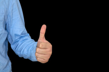 Men's thumbs up hand in front of black background