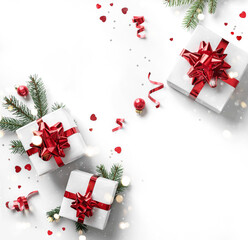 Christmas fir branches, gift boxes with red ribbon, red decoration, sparkles and confetti on white...