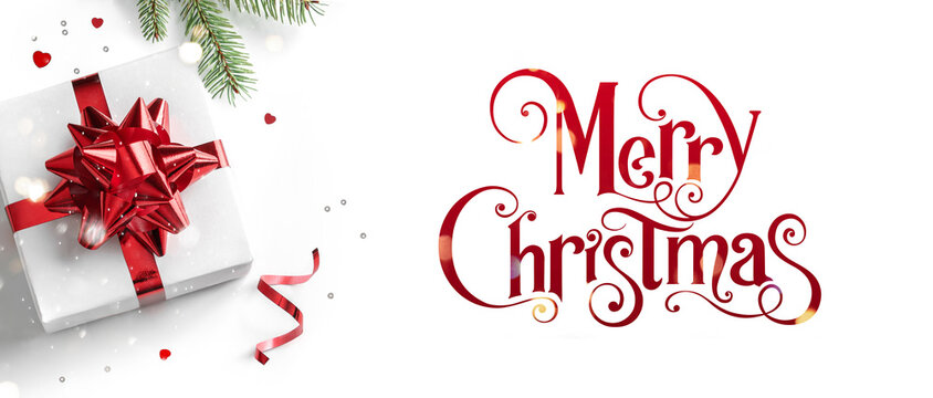 Merry Christmas text on white background with gift boxes, ribbons, red decoration, fir branches, bokeh, sparkles and confetti. Xmas and New Year greeting card, bokeh, light. Flat lay, top view, banner