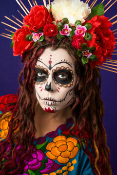 Dia de los muertos - Day of The Dead. Calavera Catrina in Halloween. Close-up portrait young woman with sugar skull make up, flowers and colorful traditional mexican dress. Holy Death - Santa Muerte.