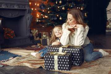 Beautiful mother in a white sweater. Family with cristmas gifts. Little girl near christmas tree