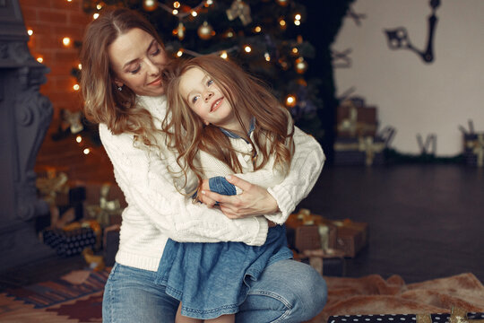 Beautiful mother in a white sweater. Family with cristmas gifts. Little girl near christmas tree