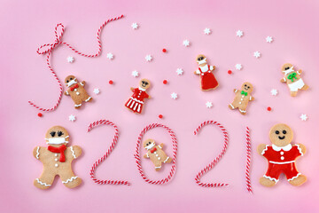 Happy new year greeting card with  gingerbread man cookies and 2021 year made from  twisted string on pink background. Flay lay ,top view.マスクをしたジンジャーマンクッキー　2021