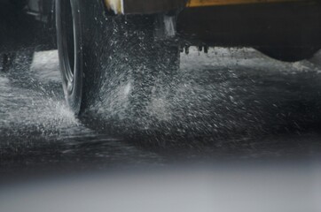Wheels of a truck driving on a wet road in rainy weather. Splashes flying from under tires.