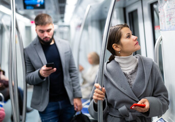 Positive woman reading from mobile phone screen in metro. High quality photo