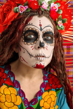 Dia de los muertos - Day of The Dead. Calavera Catrina or Santa Muerte - Holy Death drinks cocktail from skull Halloween. Portrait girl with sugar skull makeup, cocktail and traditional mexican dress.