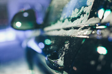 Obraz na płótnie Canvas snow on the door of a black car close-up.