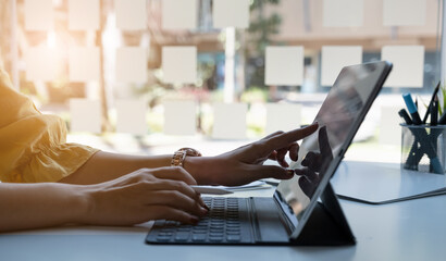 Close up hand of businesswoman with digital tablet with blank screen on wooden desk.