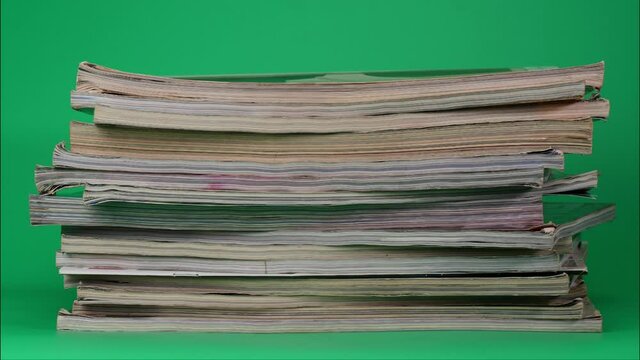 Stop Motion Animation, Large pile of books stacked together on green background.