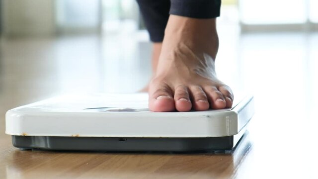 Slow motion video A woman walks in her house and she walks on the scale to Check her body weight on the manual weight scale. Concept of healthy lifestyle and sport