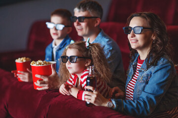 Family mom father and children are watching a projector, TV, cinema, movies with popcorn in the cinema. High quality photo.