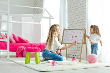 Happy loving family. Mother and daughter in the children's room. Funny mom and lovely baby having fun indoors. Cute little girl is playing with a woman. High quality photo.