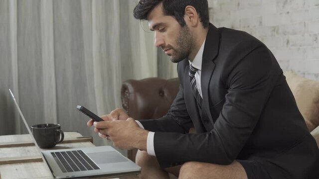 Footage B roll A Cheerful guy is working in office making mobile phone call and using laptop taking notes in notebook. Business communication. Work from home , business technology concept. 