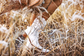 close up of young woman legs wearing cowgirl boots on the field - 386549911