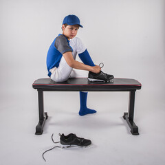 Boy baseball player on bench tying his shoes