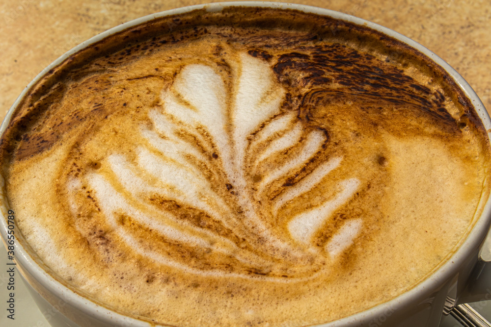 Wall mural cup of coffee cappuccino with a picture on the table