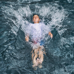 Child falling backward into water creating a big splash