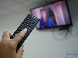 closeup of hand with the remote control television and presses the button.