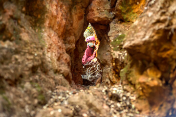 A teenage girl wearing a protective mask peeps through a crack in a rock. Concept of hiking in...