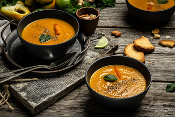 Homemade carrot soup with baked peppers and cheese, lime juice and ginger, served with nuts and fresh mint
