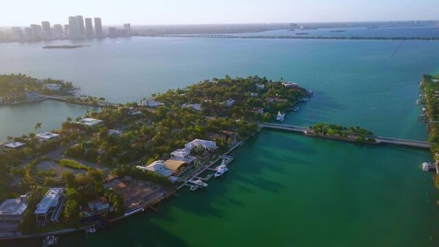 Aerial view towards a bridge and a road, luxury homes and houses, in Rivo Alto of the Venetian islands, during sunrise, in Miami, Florida - tilt down, drone shot