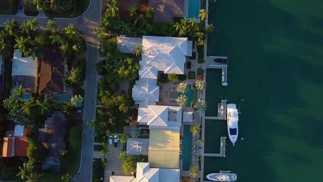 Aerial view rising above luxury villas and houses, during sunrise, on the coast of Rivo Alto isle in the Venetian islands, in Miami, Florida - top down, drone shot