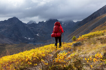 Woman Backpacking on Scenic Hiking Trail to Lake surrounded by Mountains during Fall in Canadian...